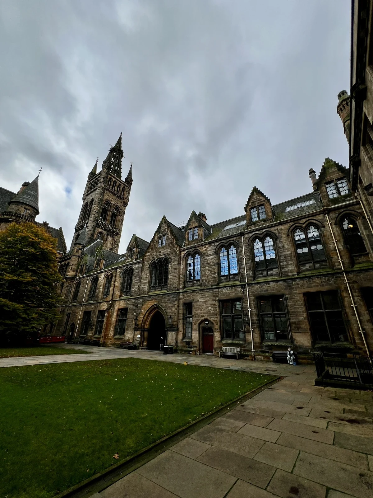 Cour de l’université de Glasgow, façades de pierre et tour sous un ciel couvert.