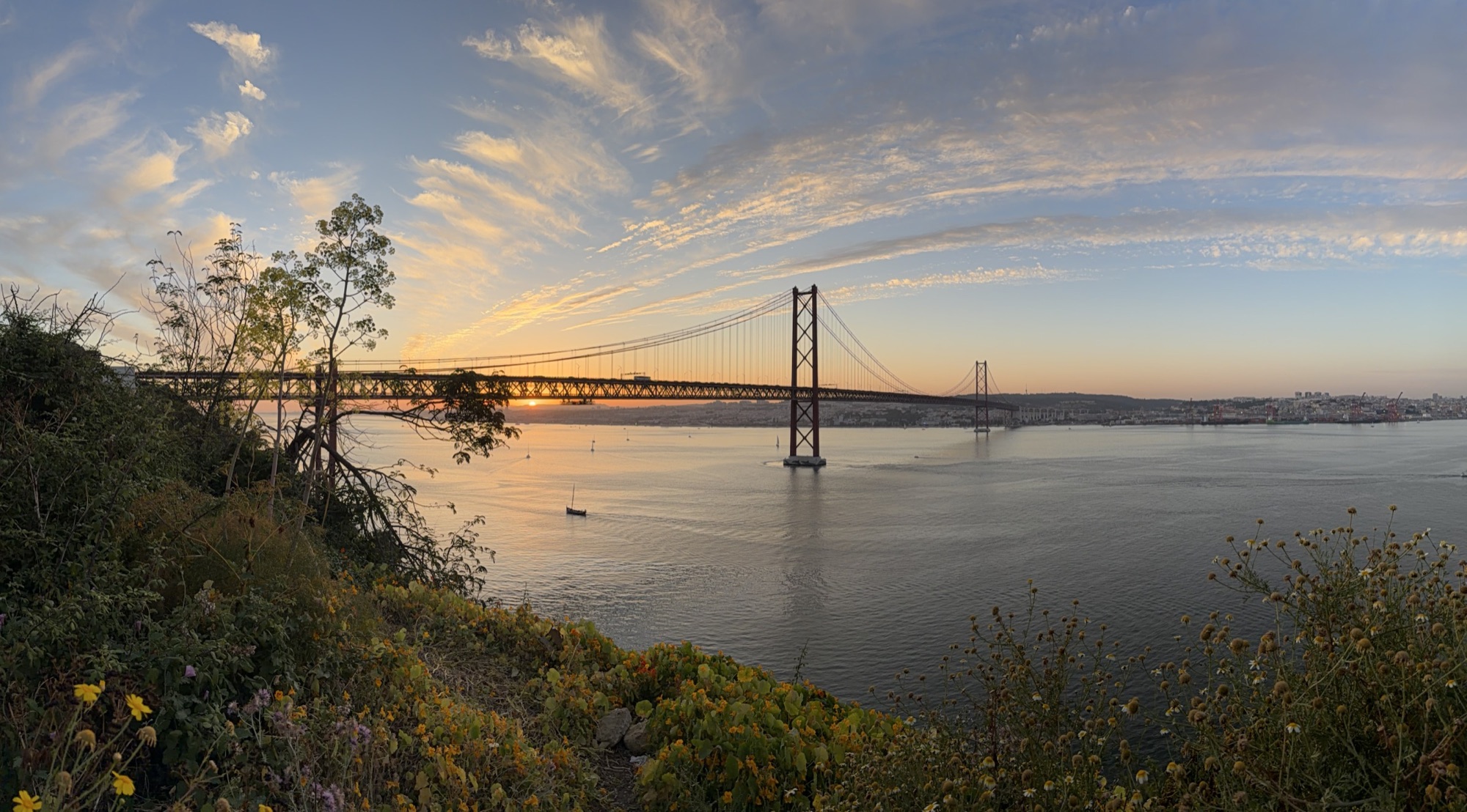 Le soleil se couche derrière le pont du 25 Avril sur le Tage, à Lisbonne.